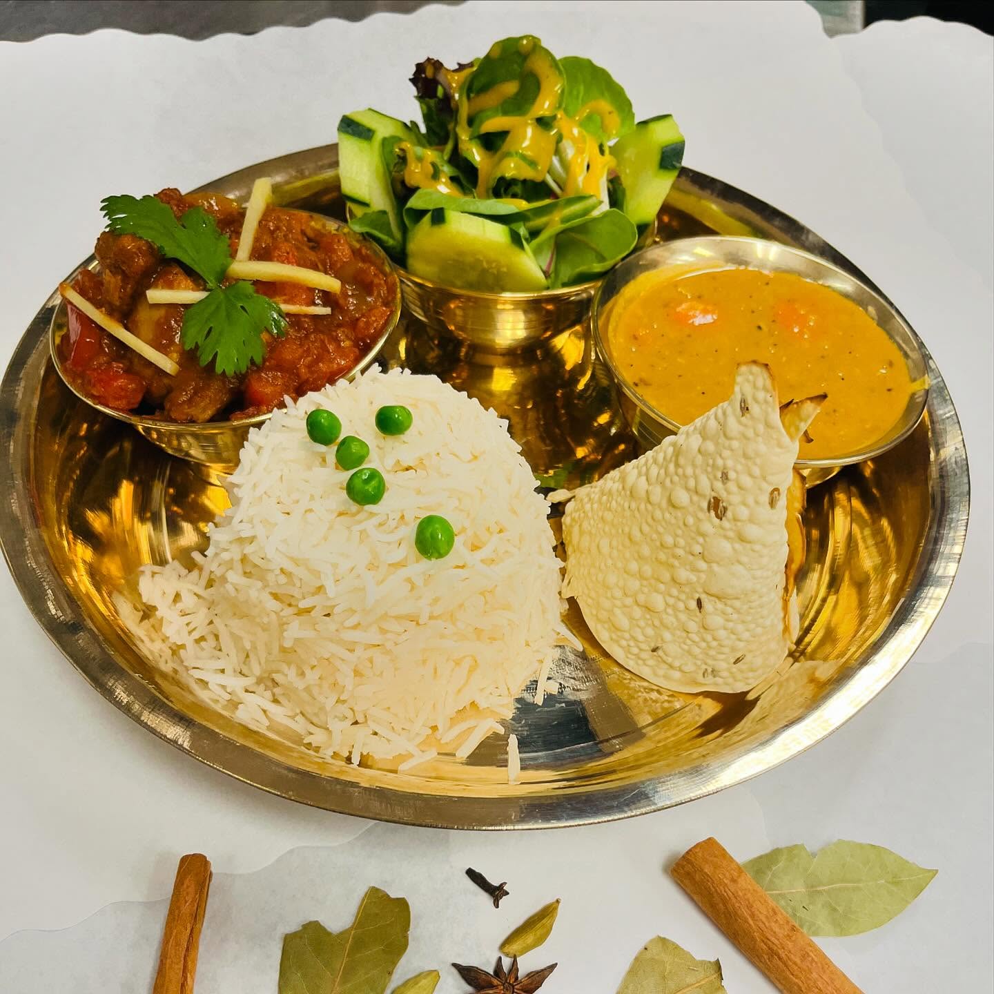 A complete meal platter featuring a variety of dishes, including rice, lentils, vegetables, and pickles.